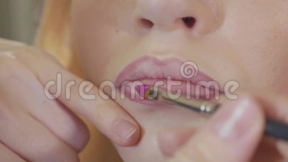 年轻的化妆师在模特的嘴唇上涂口红视频的预览图