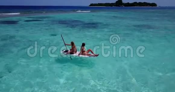 V08319两个漂亮的年轻女孩坐在冲浪板上在温暖的蓝色海水中鸟瞰天空视频的预览图