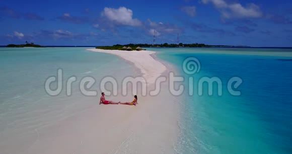 V09025两个人浪漫的年轻人夫妇在海滩上坐着日光浴从空中无人机可以看到白色的海滩视频的预览图