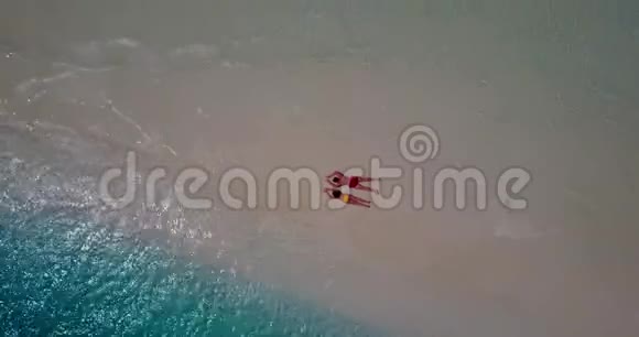 V08520两位年轻人浪漫的一对日光浴无人驾驶飞机在沙滩上飞行沙滩上白沙美丽视频的预览图