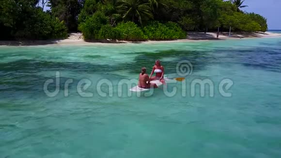 V08182两个漂亮的年轻女孩坐在冲浪板上在温暖的蓝色海水中鸟瞰天空视频的预览图