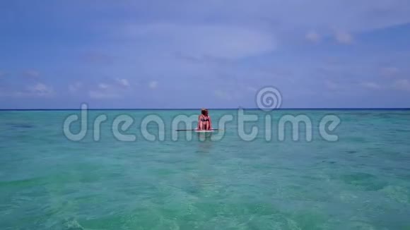 V08384两个漂亮的年轻女孩坐在冲浪板上在温暖的蓝色海水中鸟瞰天空视频的预览图