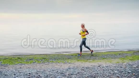 一个年轻的女人沿着海边或湖边慢跑秋天早晨视频的预览图
