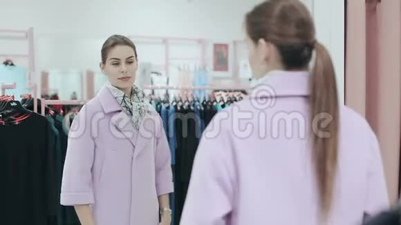 年轻苗条的女士穿着一件外套女人在镜子前购物和检查粉红色外套风格和风格视频的预览图