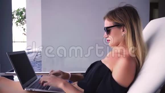 自由职业者妇女坐在游泳池附近的休息室里在笔记本电脑上工作动作缓慢视频的预览图