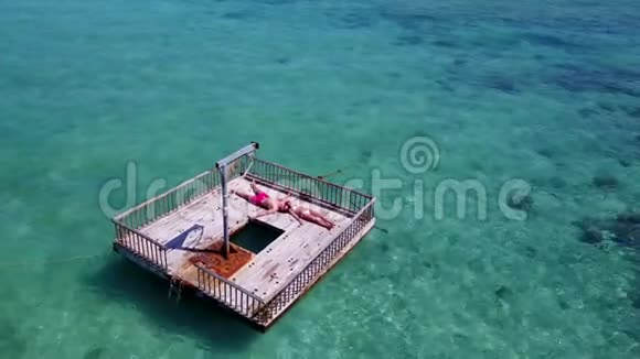 V08557两位年轻人在美丽清澈的水蓝色海水中在浮舟上享受浪漫的日光浴视频的预览图