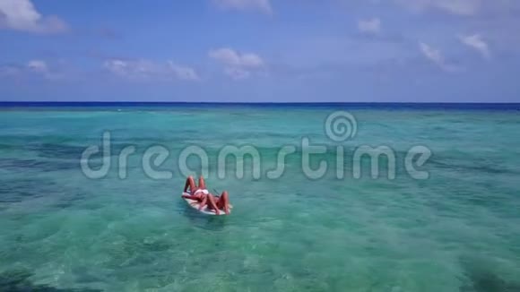 V08209两个年轻漂亮的女孩坐在冲浪板上在温暖的蓝色海水中俯瞰空中景色视频的预览图