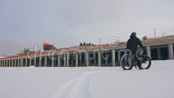 专业的极限运动员自行车站在户外一辆胖自行车骑自行车者在冬天的雪林中退缩男人走路视频的预览图