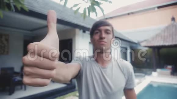 快乐的年轻人伸出大拇指在院子里的室外微笑视频的预览图