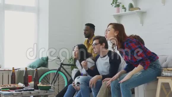 快乐的年轻朋友在电视上观看体育比赛在家庆祝最喜爱的球队胜利视频的预览图