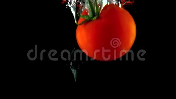 一个成熟的红番茄上面有绿色的叶子落在水里非常慢的镜头视频的预览图