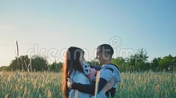 幸福的家庭在一片麦田中的绿色小穗在阳光下他们一起拥抱一个小女儿美丽美丽视频的预览图