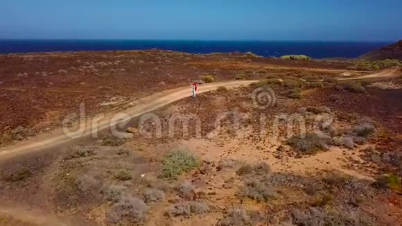 鸟瞰一位妇女徒步旅行并在加那利群岛特内里费海岸附近拍摄火山表面的照片视频的预览图