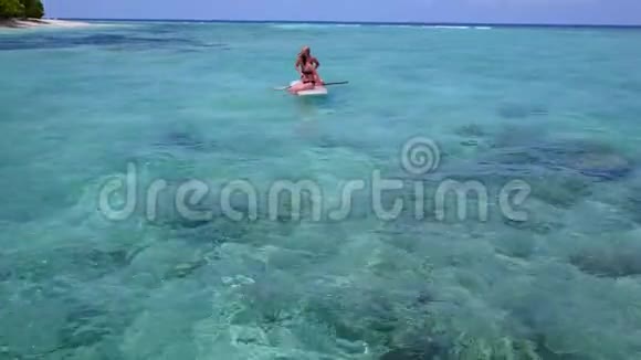 V08382两个漂亮的年轻女孩坐在冲浪板上在温暖的蓝色海水中鸟瞰天空视频的预览图
