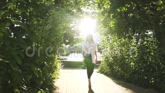 时尚自信的年轻女性慢动作在阳光公园散步视频的预览图