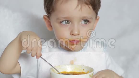 这个男孩高兴地用勺子从盘子里吃汤特写运动相机滑块一个男孩坐在那儿吃饭视频的预览图