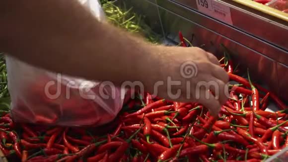 男性顾客在购物时将辣椒放入食品超市的塑料袋中慢动作视频的预览图