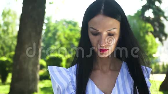 夏日公园背景下美丽的黑发美女在镜头外的肖像视频的预览图