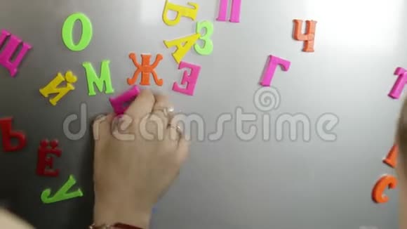 小保姆带着一个小男孩学习磁铁上的字母视频的预览图
