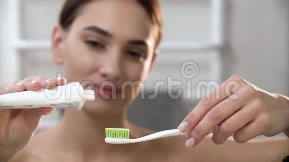 牙齿卫生涂牙膏在牙刷上的女人视频的预览图
