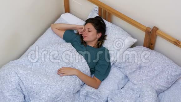 瞌睡女孩的俯视图醒来早晨躺着一条白色的毯子视频的预览图