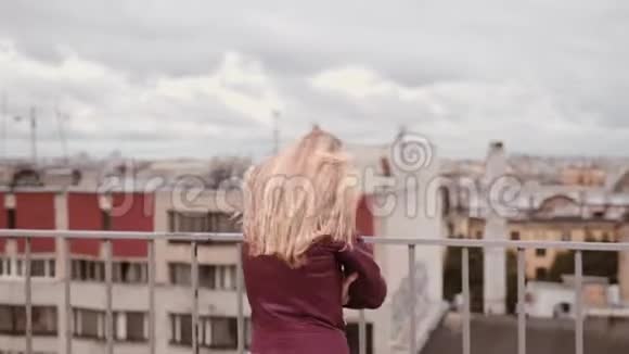穿皮夹克的冻僵的女人在风中站在屋顶上感到寒冷视频的预览图
