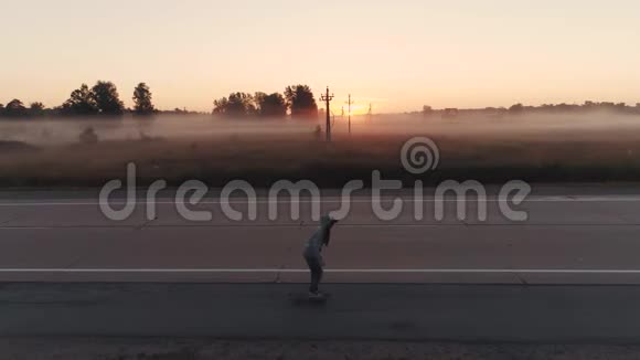 空中飞行日落时女孩正骑在滑板上沿着一条空荡荡的公路行驶视频的预览图
