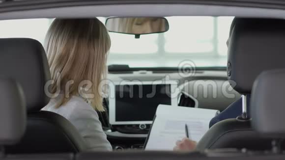 4年轻女子在汽车的船舱里签订了一份买车的合同视频的预览图