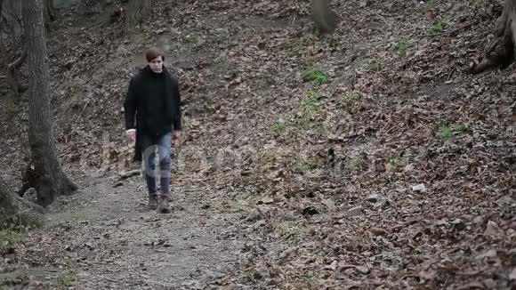 愤怒的年轻人走在森林里带着烦恼扔石头无助的愤怒视频的预览图