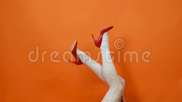 性感的长腿穿着高跟鞋红色的鞋子白色的鱼网袜橙色的背景复古风格视频的预览图