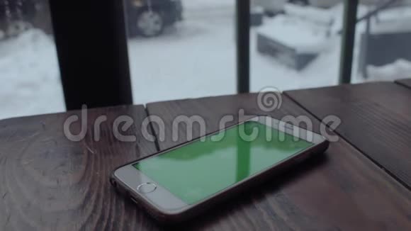 男人手在咖啡馆的木桌上打绿色屏幕手机视频的预览图