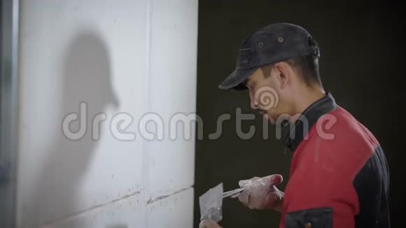 一个当建筑工人的年轻人在瓷砖之间的接缝上铺了一道白浆他用一把铲子视频的预览图