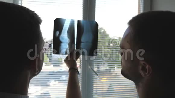 医院里的医务人员在寻找和分析x光指纹医生互相咨询两位男性医生观察核磁共振视频的预览图