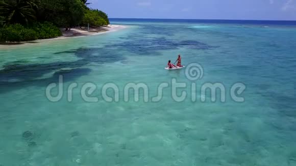 V08373两个漂亮的年轻女孩坐在冲浪板上在温暖的蓝色海水中鸟瞰天空视频的预览图