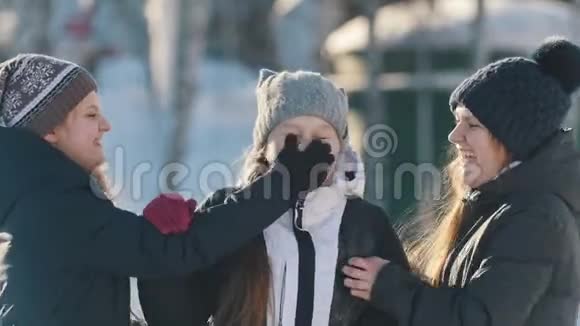 三个十几岁的女孩在冬天在外面摆姿势拥抱和微笑的肖像视频的预览图