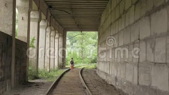 小女孩走在隧道里的铁轨上视频的预览图
