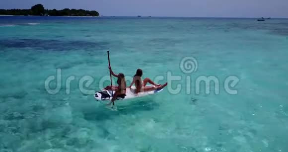 V08320两个漂亮的年轻女孩坐在冲浪板上在温暖的蓝色海水中鸟瞰天空视频的预览图