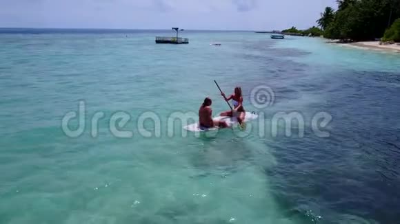 V08184两个漂亮的年轻女孩坐在冲浪板上在温暖的蓝色海水中俯瞰空中景色视频的预览图