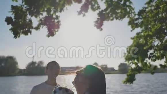 一个三口之家在阳光照射下的湖岸绿树下妈妈把她扔了视频的预览图