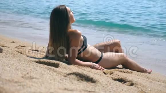 穿比基尼的年轻女孩躺在海边和日光浴美丽的白种人女性夏天在海边放松视频的预览图