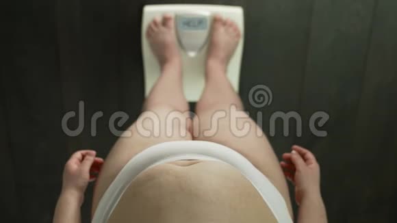 胖肚子站在天平上的超重女孩屏幕上的文字帮助愤怒视频的预览图