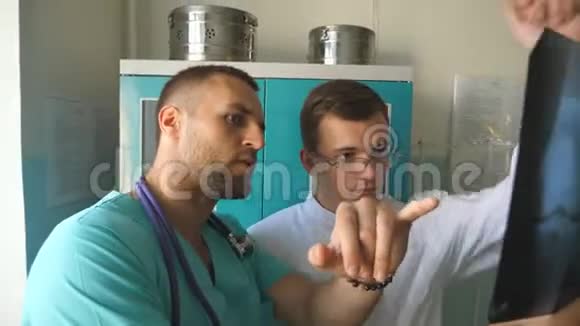 男性医务人员在看x射线图像时互相咨询两名白种人医生观看核磁共振成像并讨论视频的预览图