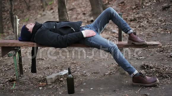喝了太多酒后生病的青少年沮丧的家伙躺在长凳上视频的预览图