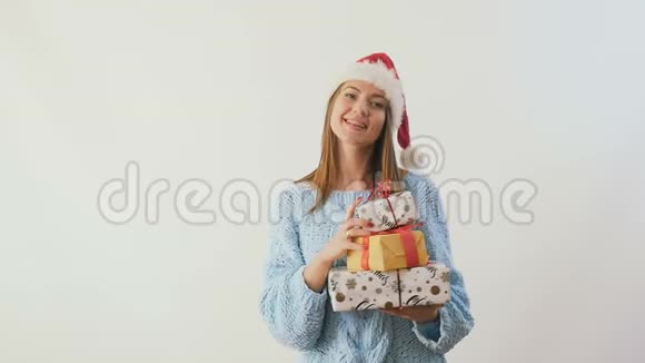 圣诞老人帽子里的快乐女孩带着礼物在白色背景下缓慢地跳舞视频的预览图