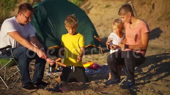 父母和孩子在火堆上做饭视频的预览图