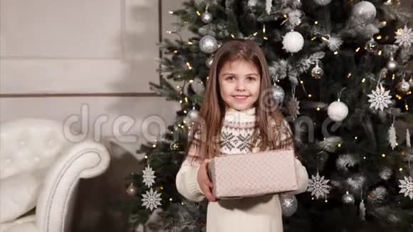 一个小而快乐的女孩拿着一个装有圣诞礼物的盒子并送给她的肖像视频的预览图
