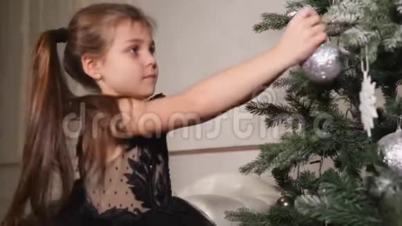 快乐的女孩在假期前穿了一棵圣诞树宝宝拿着明亮的球视频的预览图