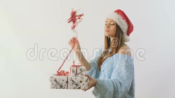 圣诞老人帽子里可爱女孩挥舞着一根带有丝带的装饰棒视频的预览图