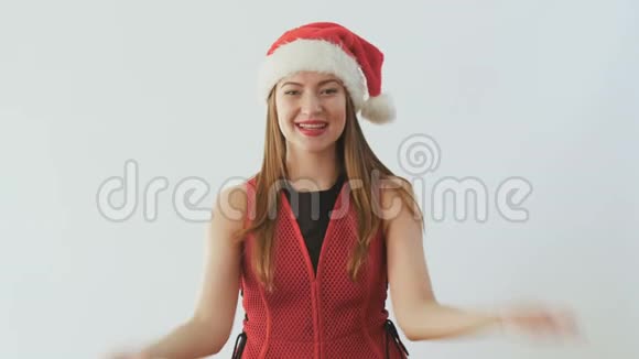 戴着圣诞老人帽子的年轻女孩发出一个空中亲吻微笑着面对白色背景视频的预览图