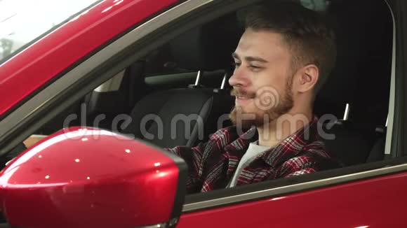 英俊的年轻人舒适地坐在他的新车里对着镜头微笑视频的预览图